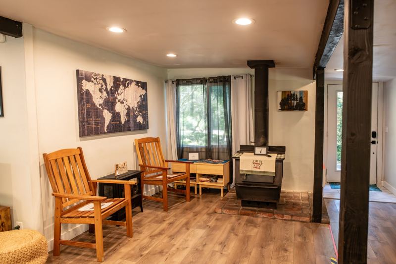 Living room with wooden chairs, a world map, and the wood stove nook
