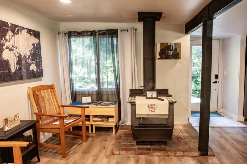 Living room corner with a wood stove and forest-view window